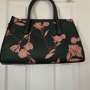 A dark green purse with pink flowers.